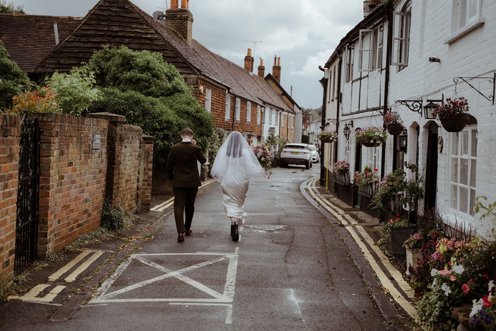 a bride and grrom are walking away from the camera in the village of Bray