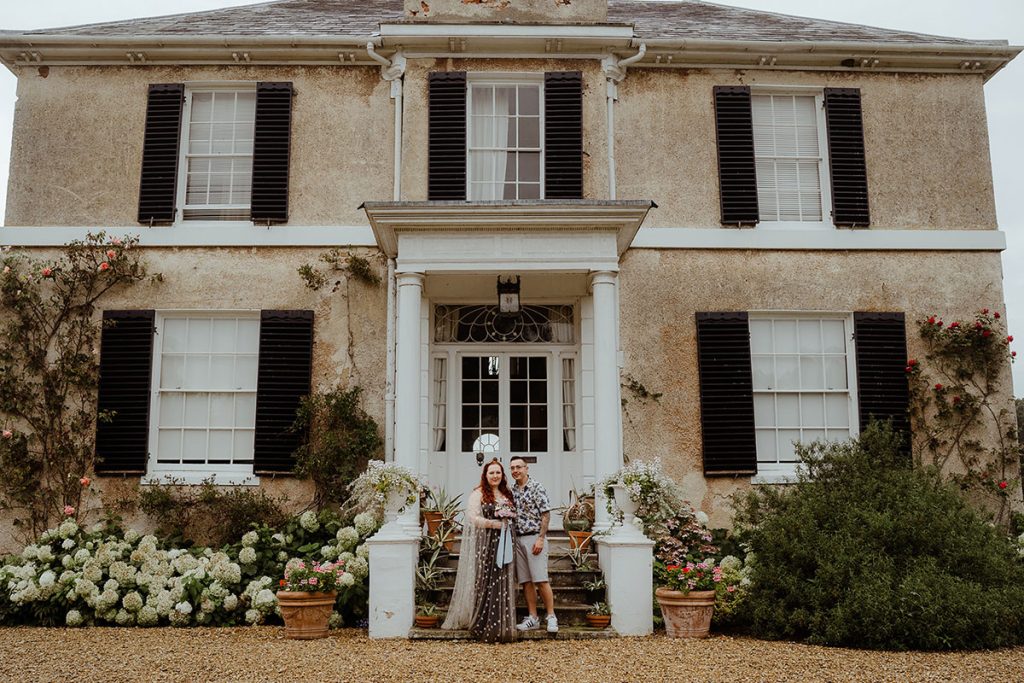 Couple posing on their wedding day in front of the house at Preston Court in Kent.
