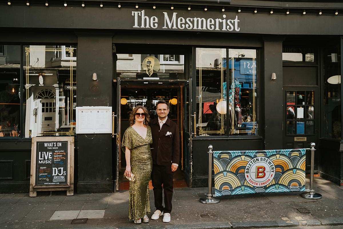 A couple standing outside the Mesmerist Pub in Brighton on their wedding day