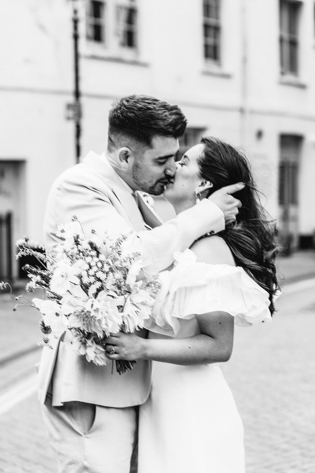 Couple embrace on their wedding day with the groom holding the bride's face while they kiss by brighton wedding photographer lisa devlin