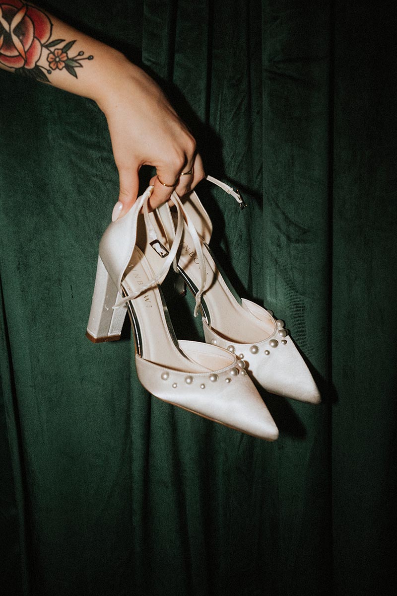 wedding detail image of a bride's shoes being held through a green velvet curtain at her wedding at the joker pub in Brighton