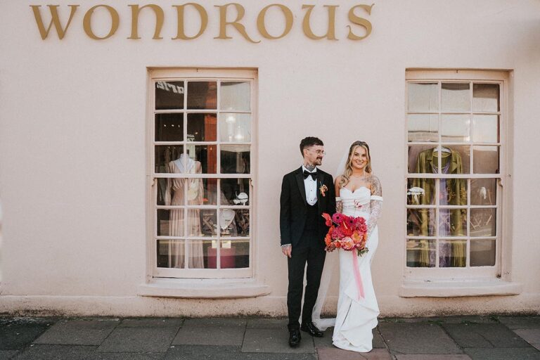 Couple pose outside a pink shop in Brighton before going to their reception at The Joker Pub
