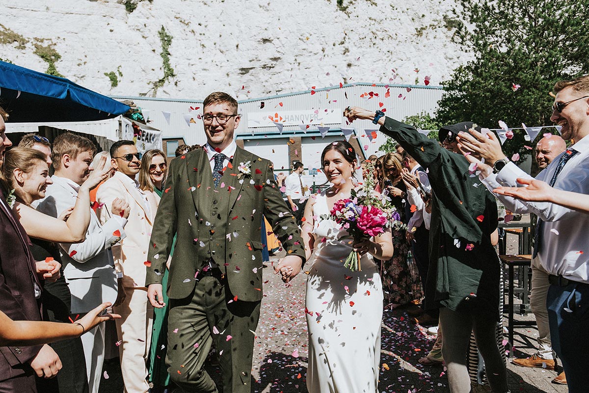 Bride and groom confetti exit facing the cliffs, Beak Brewery wedding Sussex