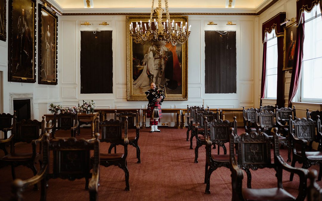 Photo of the wedding ceremony room at Windsor Guildhall, set up with chairs for a wedding with a Scottish Piper playing at the back of the room.