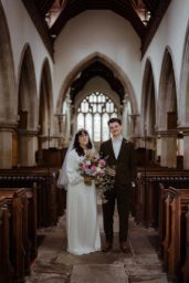 bride and groom stand in the aisle of St Michael's church in Bray, Berkshire